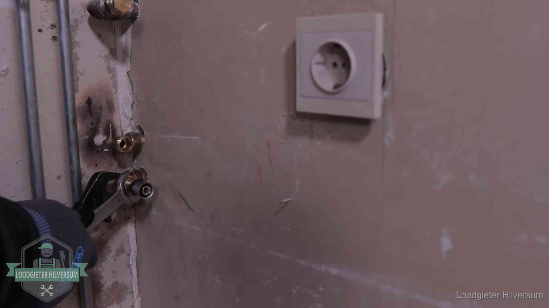 Monteur draait een perskoppeling vast op een leidingaansluiting in Hilversum