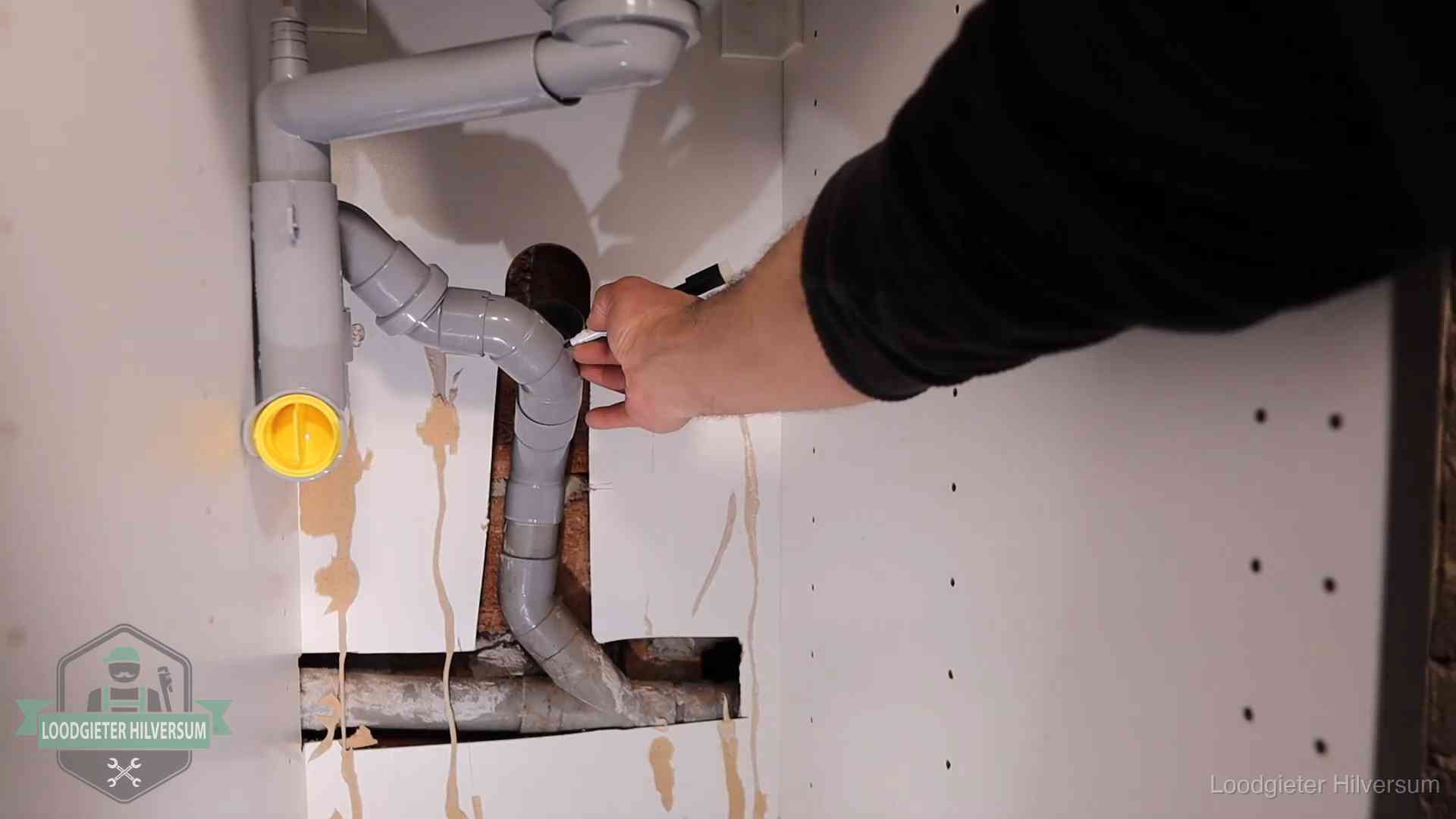 Loodgieter markeert een pvc-afvoerbuis onder een gootsteen in Hilversum