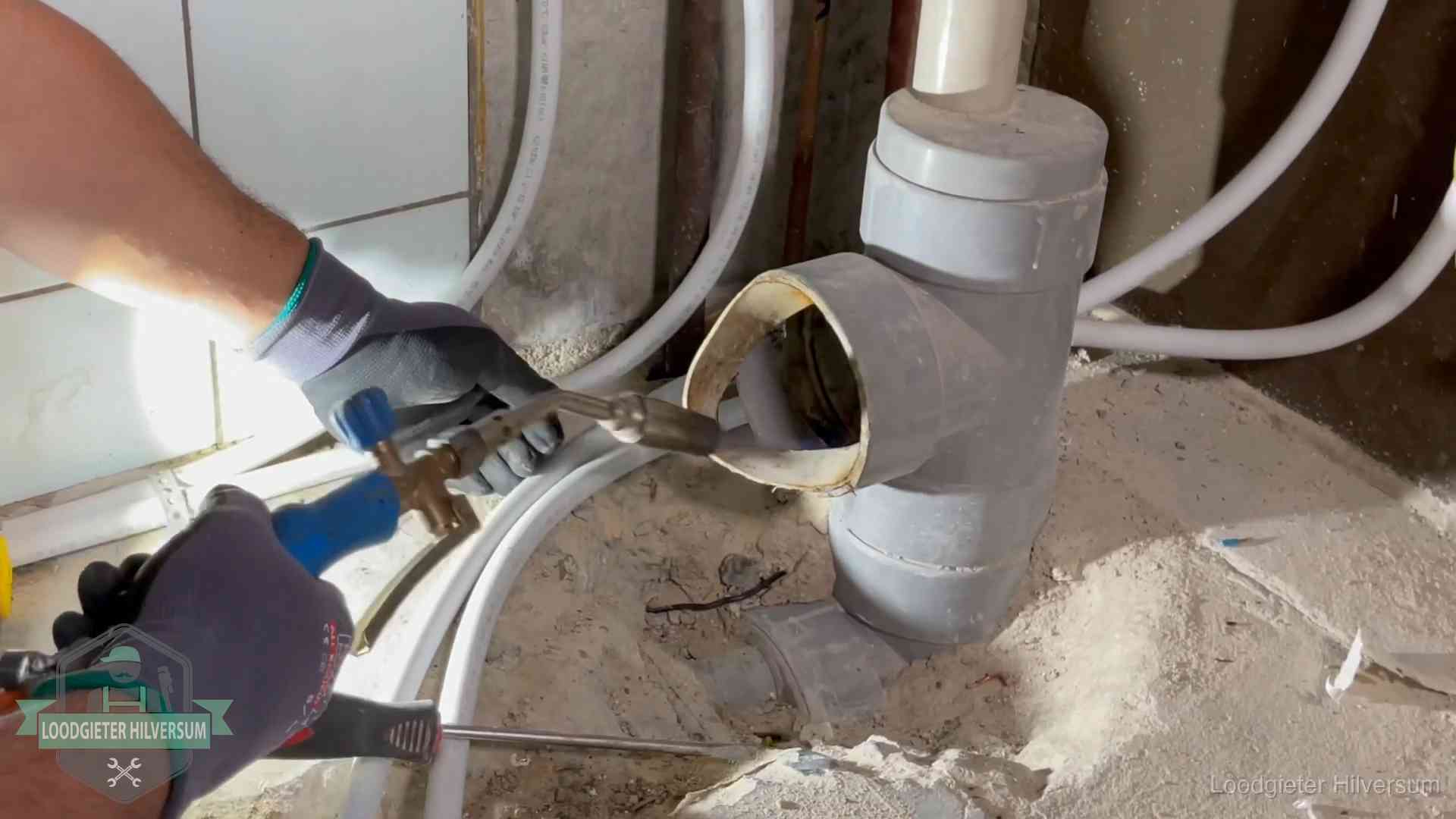 Loodgieter werkt met brander en messing kraanwerk aan leidingen in Hilversum