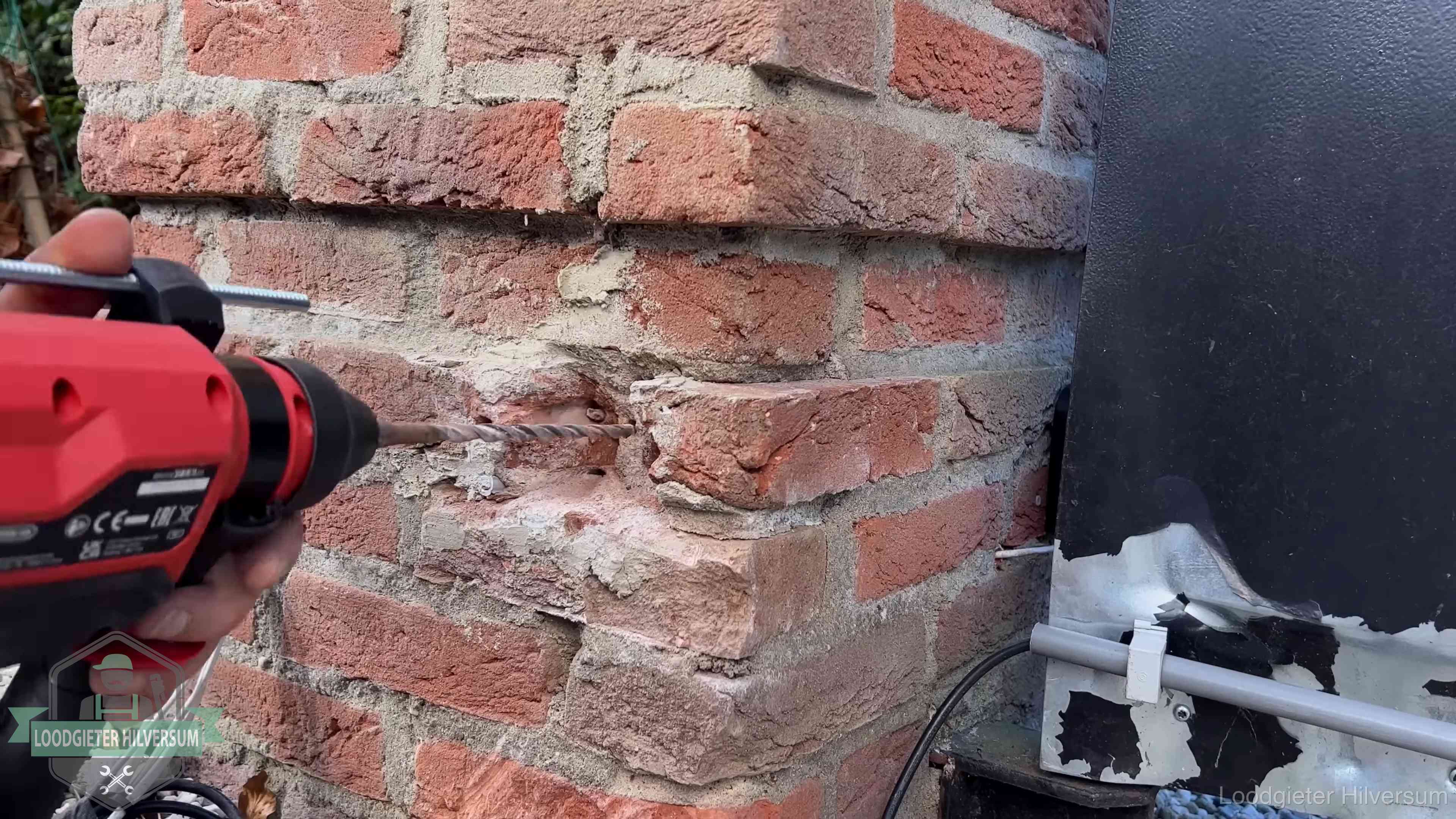 Vakman boort in de buitenmuur van een woning in de regio Hilversum