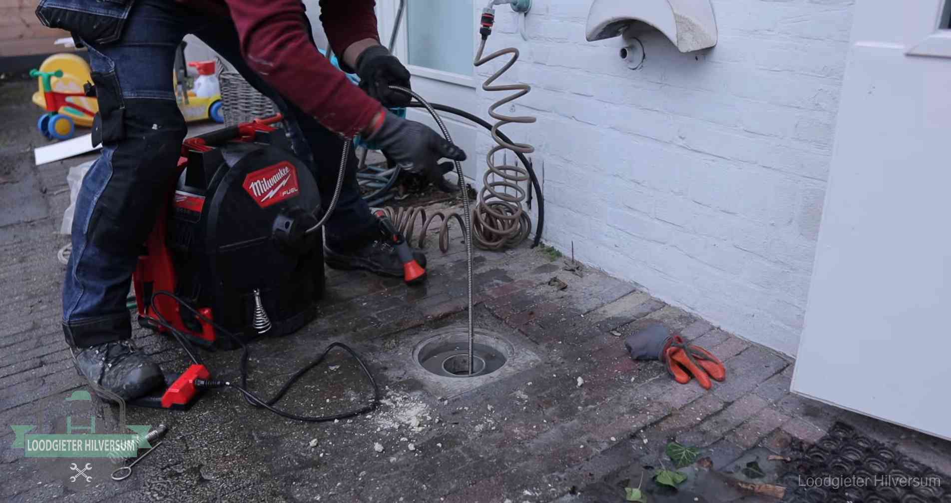 Ontstoppingsputje in de bestrating naast de gevel van een woning in Hilversum