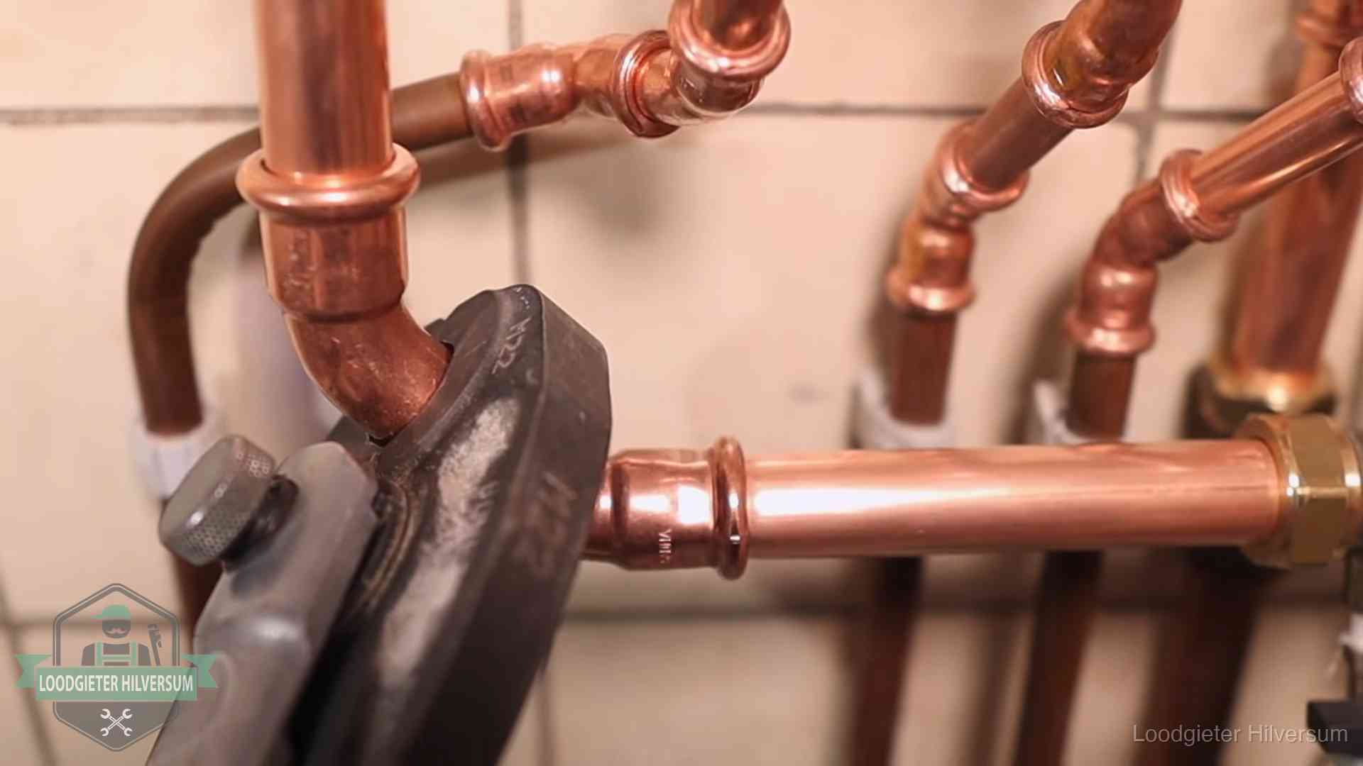 Persmachine perst een koperen fitting op nieuw leidingwerk in Hilversum