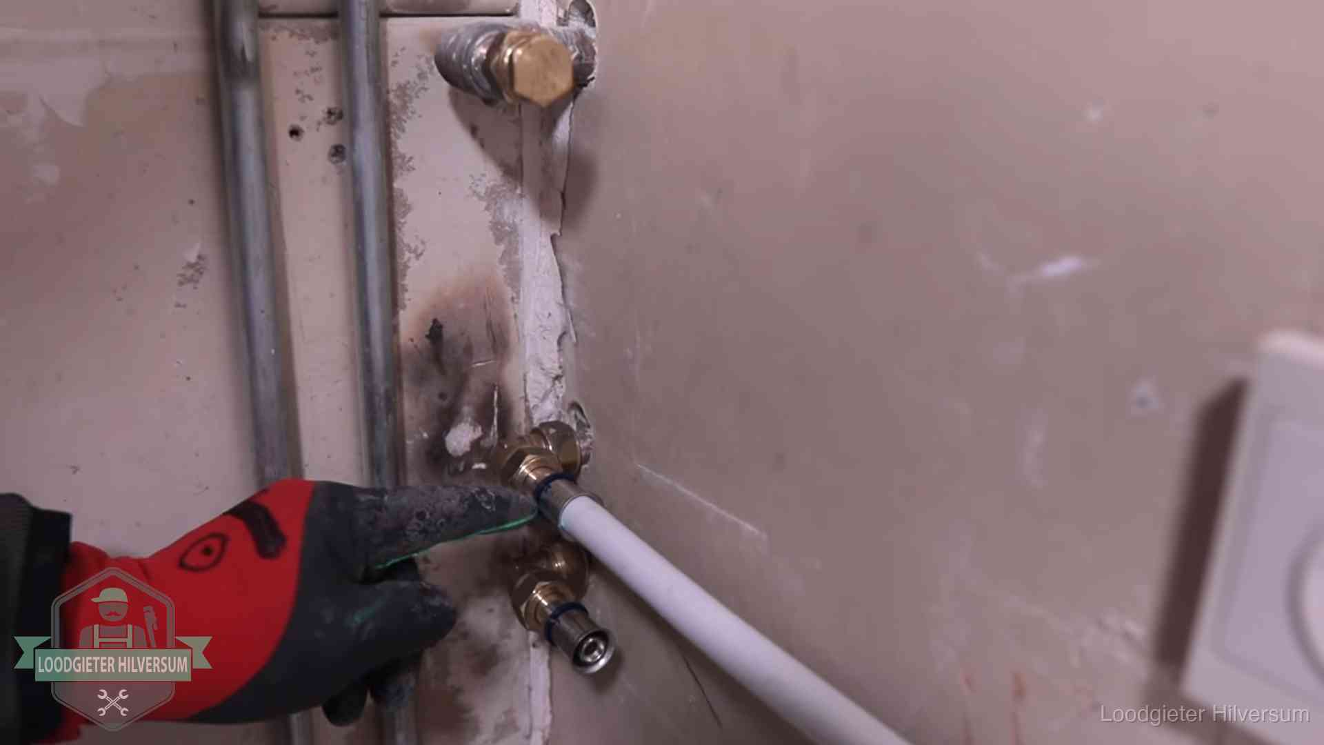 Loodgieter wijst de persfitting op nieuwe muuraansluitingen aan in een woning in Hilversum