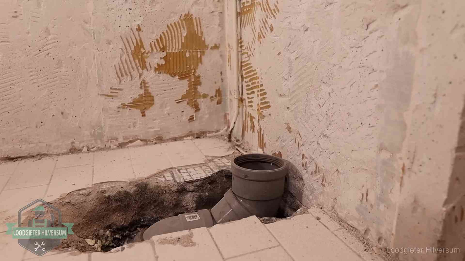 Opengebroken vloer met een nieuwe pvc-rioolbocht in een gegraven sleuf in Hilversum