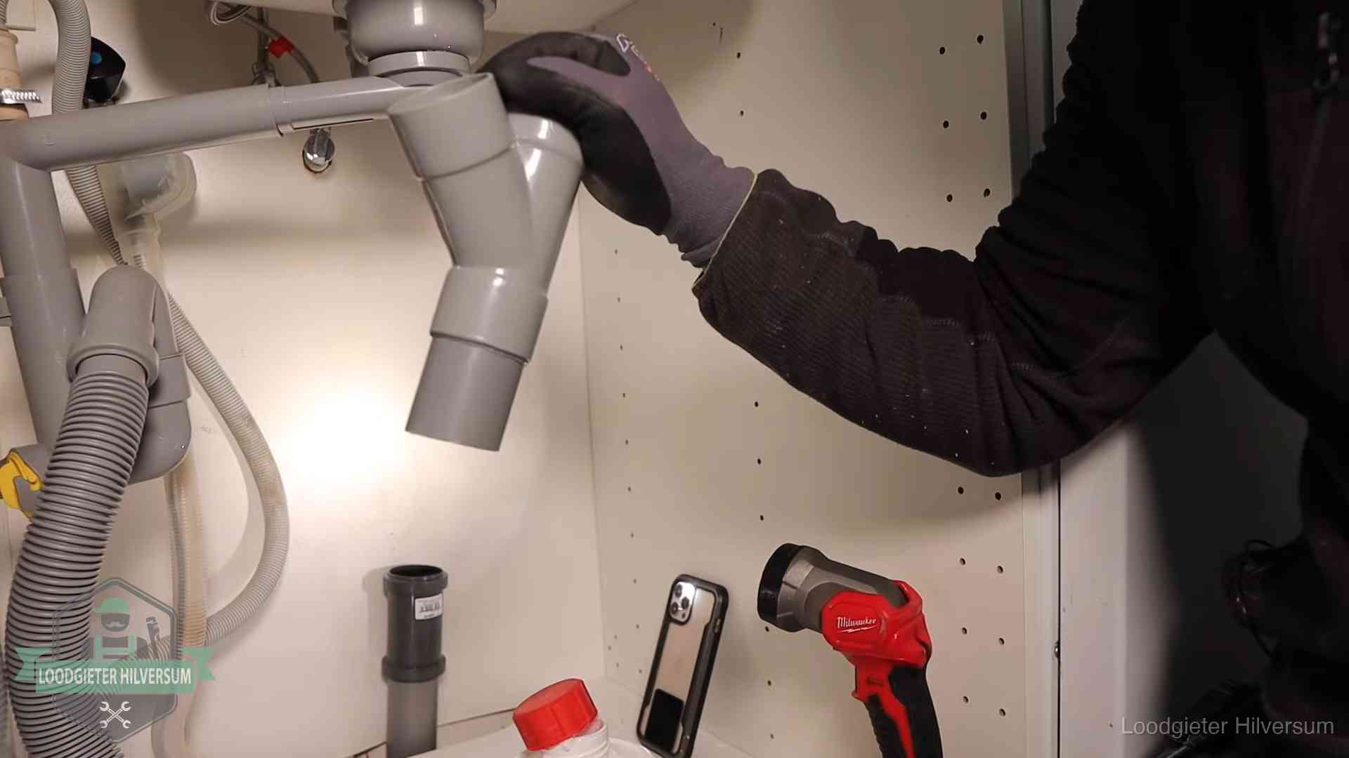 Loodgieter demonteert het sifon- en afvoerwerk onder een gootsteen in Hilversum bij stankklachten