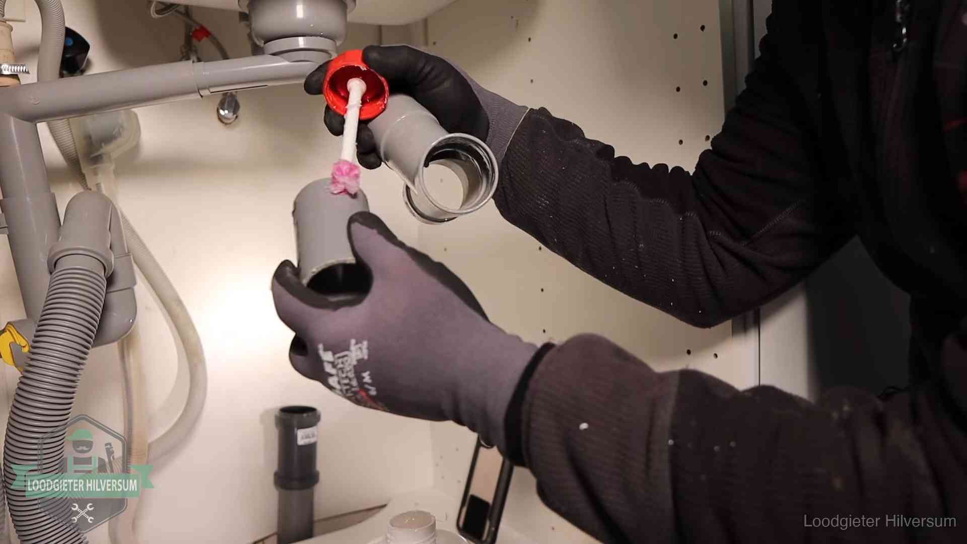 Loodgieter demonteert en reinigt de sifon onder een keukenkast in Hilversum