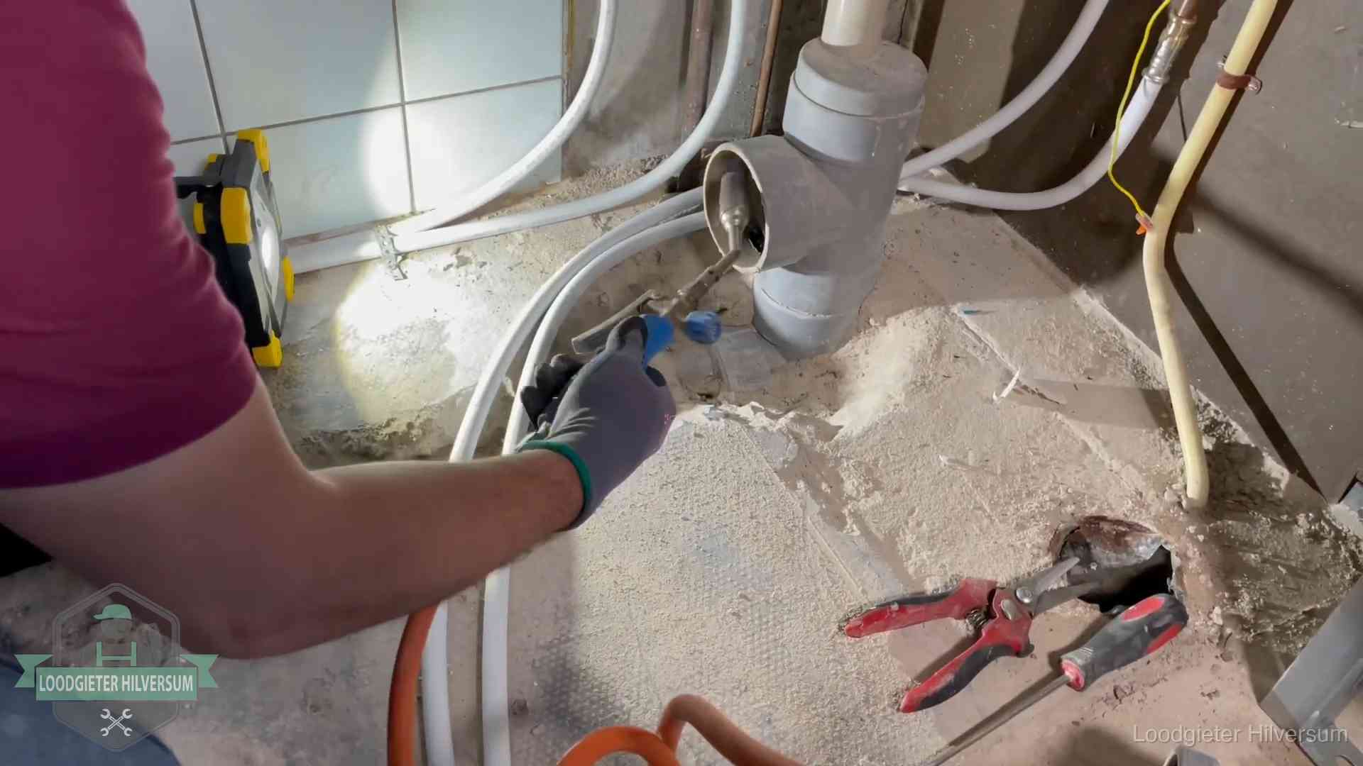 Loodgieter werkt aan leidingen bij een pvc-standleiding in een appartement in Hilversum